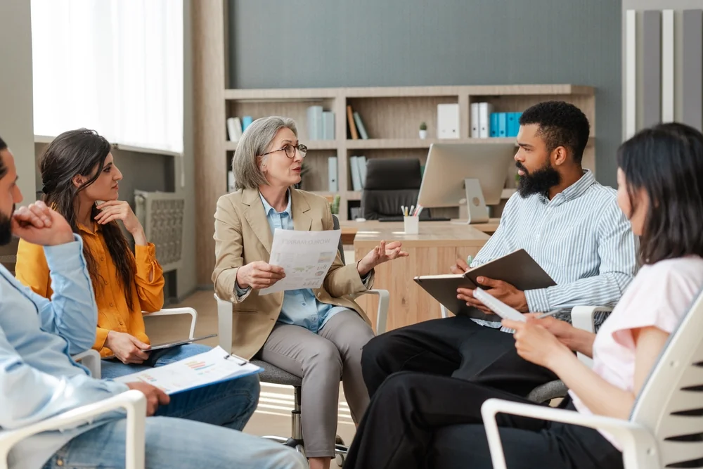 Diverse team of professionals is sitting in circle in modern office