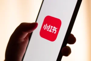 Red note app on smartphone screen in woman hands.